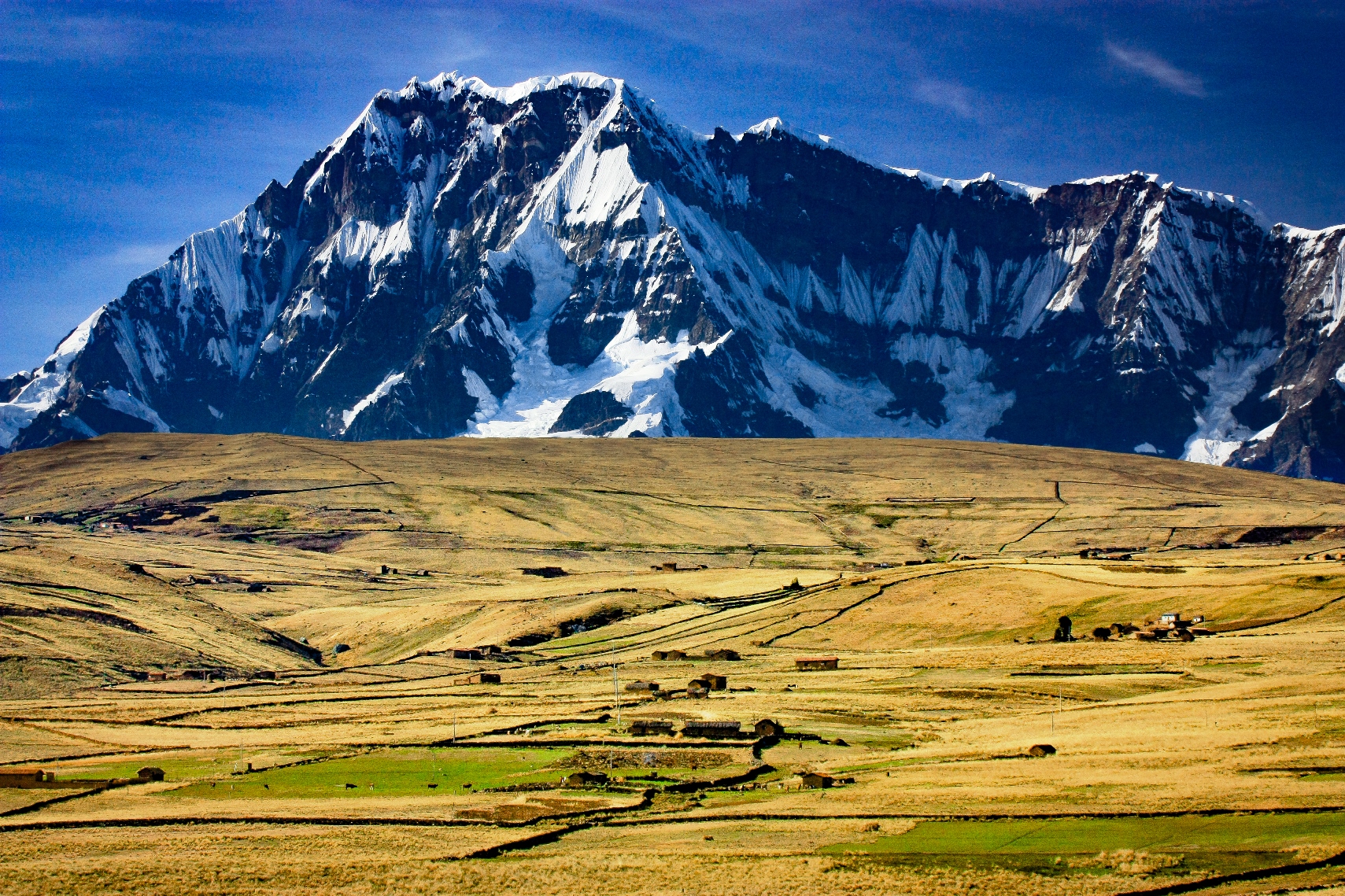 山麓に生きる集落と大草原の彼方に聳えるビルカノータ山群の主峰アウサンガテ（6,394m）